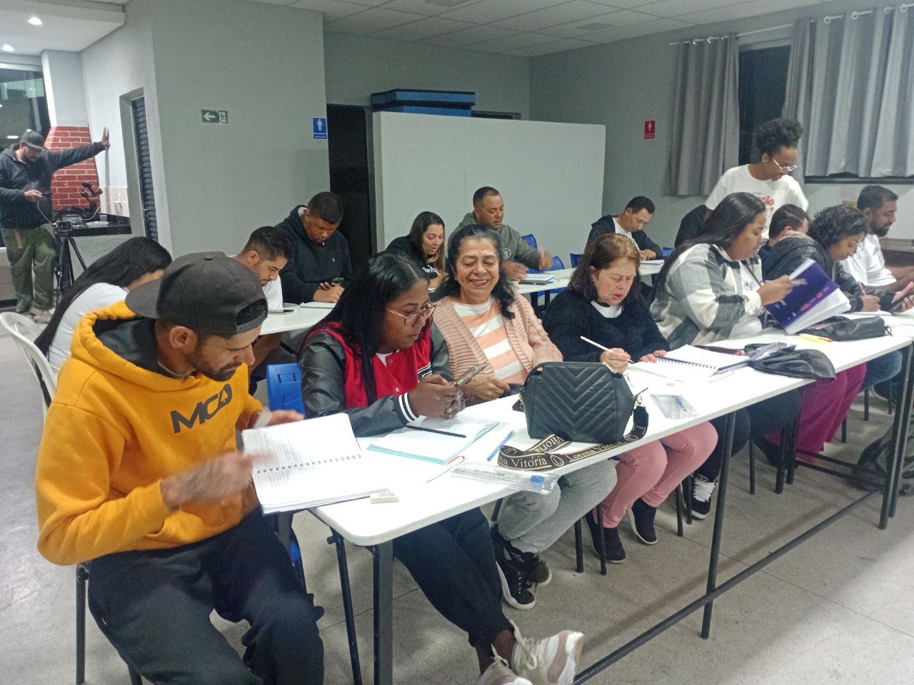 Adultos sorrindo durante formação em sala